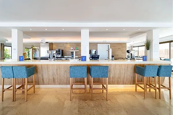 R2 Hoteles Corporativa: Bar moderno con asientos azules y ambiente elegante.