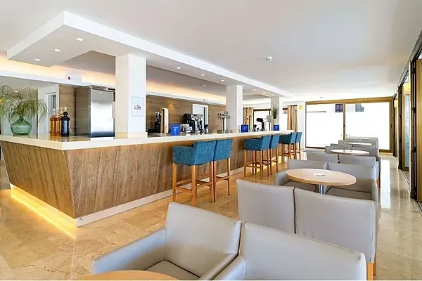 R2 Hoteles Corporativa: Bar moderno con asientos azules y ambiente elegante.