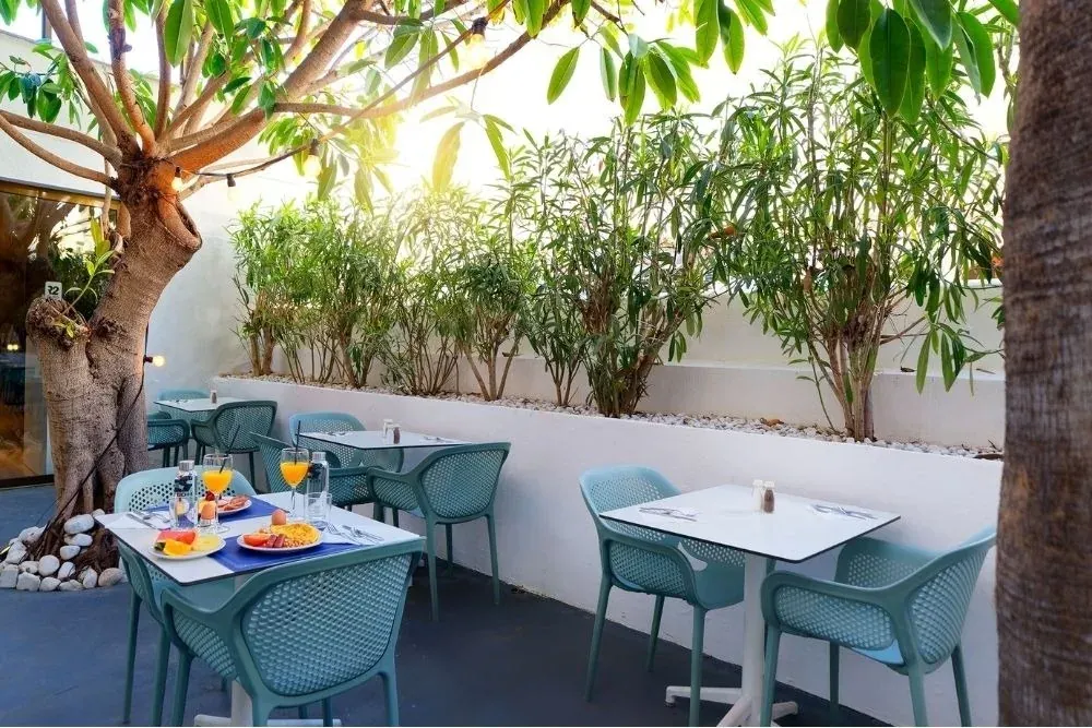 R2 Hoteles: Exterior acogedor con mesas, sillas y desayuno junto a la vegetación.
