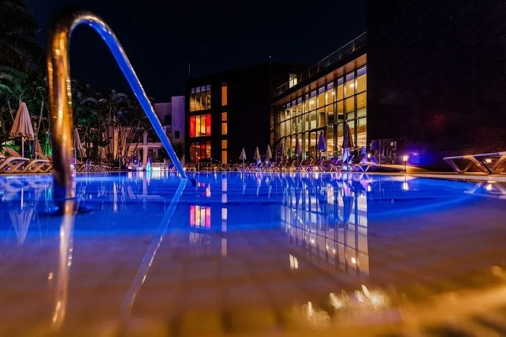 Piscina iluminada de noche con reflejos de R2 Hoteles: Corporativa.