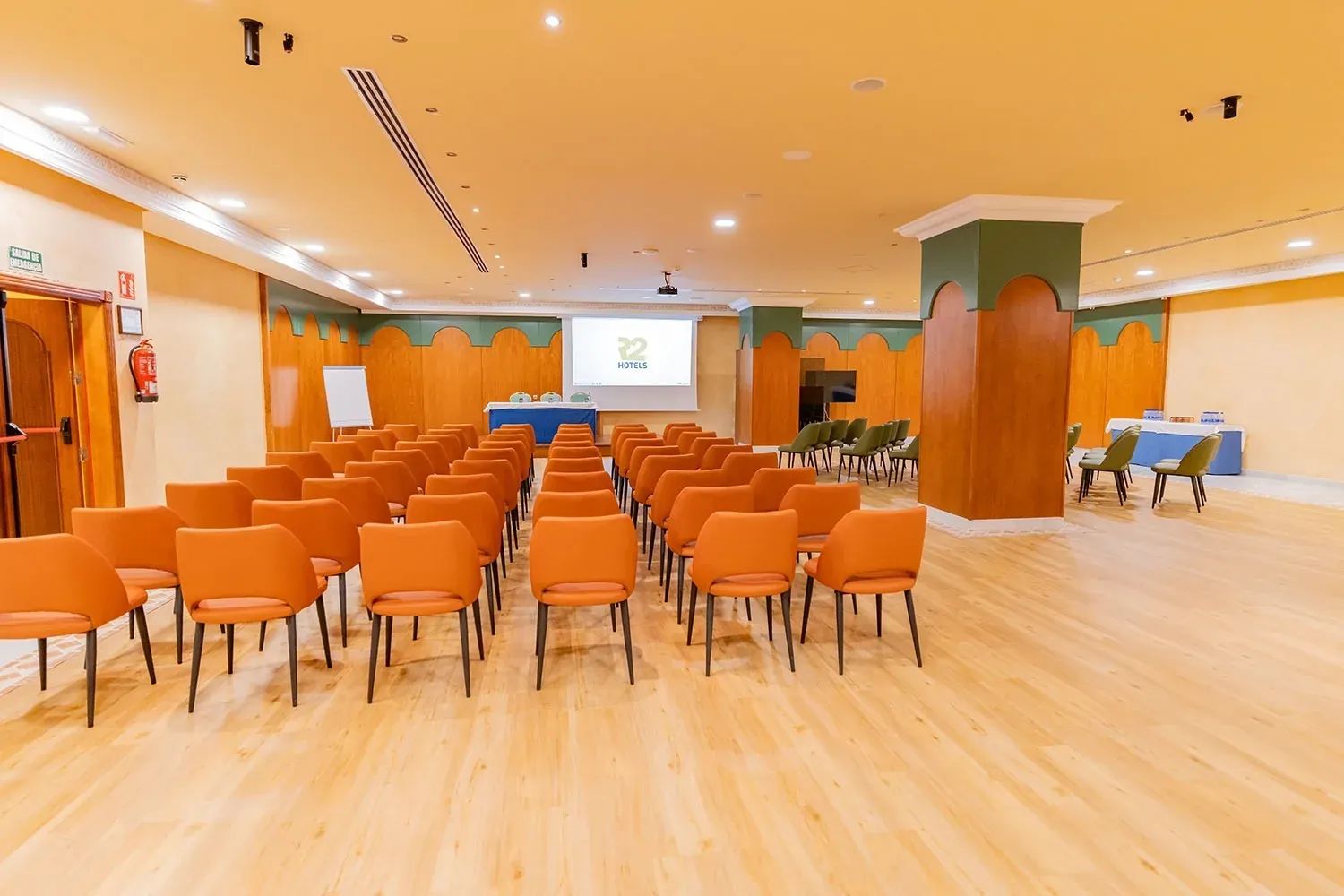 R2 Hotels Konferenzraum: Moderner Tagungsraum mit orangen Stühlen.