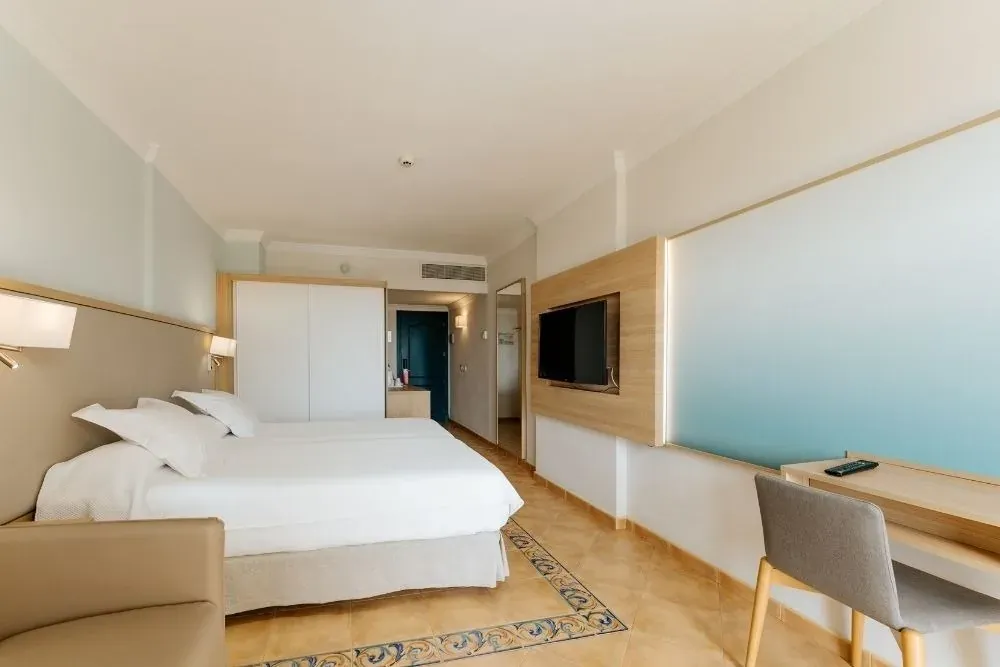 Habitación R2 Buganvilla Hotel & Spa: cama doble, TV, escritorio y sillón acogedor.