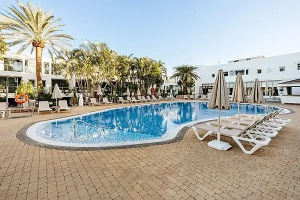 R2 Hoteles: Piscina exterior con tumbonas y vegetación tropical.