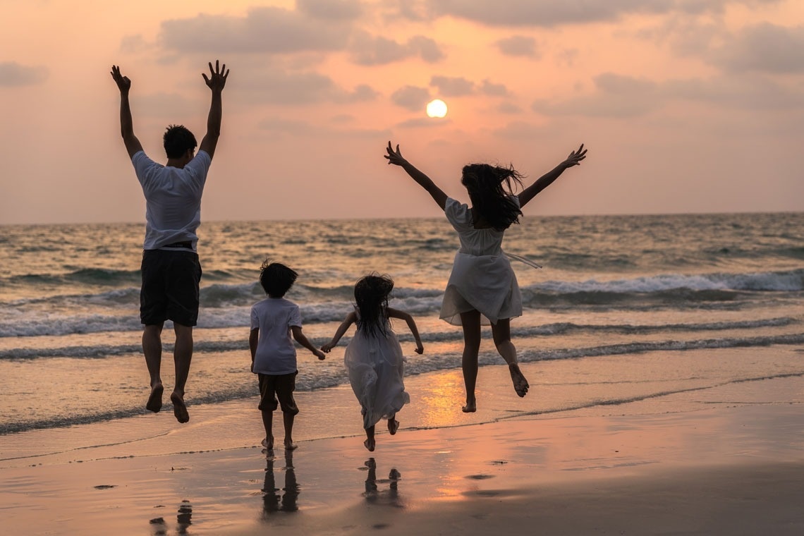 Family beach vacation at sunset with Travel Raintree Corpo.