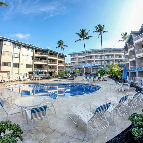 Travel Raintree Corpo: Resort pool with lounge chairs and buildings under a blue sky.