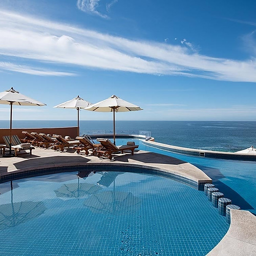 Travel Raintree Corpo: Luxury infinity pool with ocean views, lounge chairs, and umbrellas.