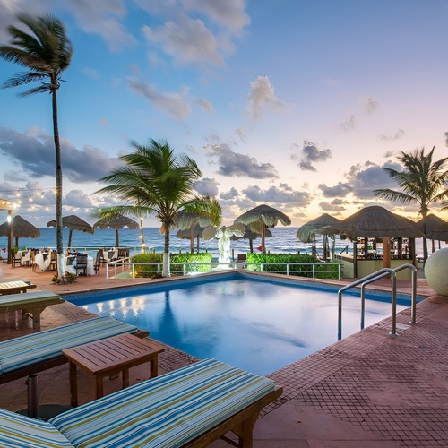 Travel Raintree Corpo: Poolside resort at dusk with ocean views and palm trees.