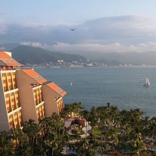 Travel Raintree Corpo hotel overlooking bay, mountains, and sailboat.
