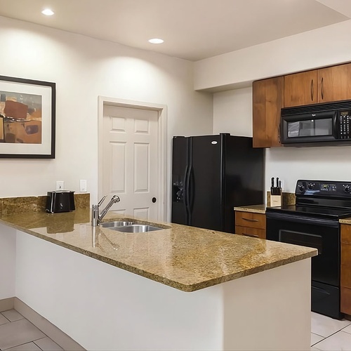 Modern kitchen with granite countertops and black appliances. Ideal for your Travel Raintree Corpo trip.