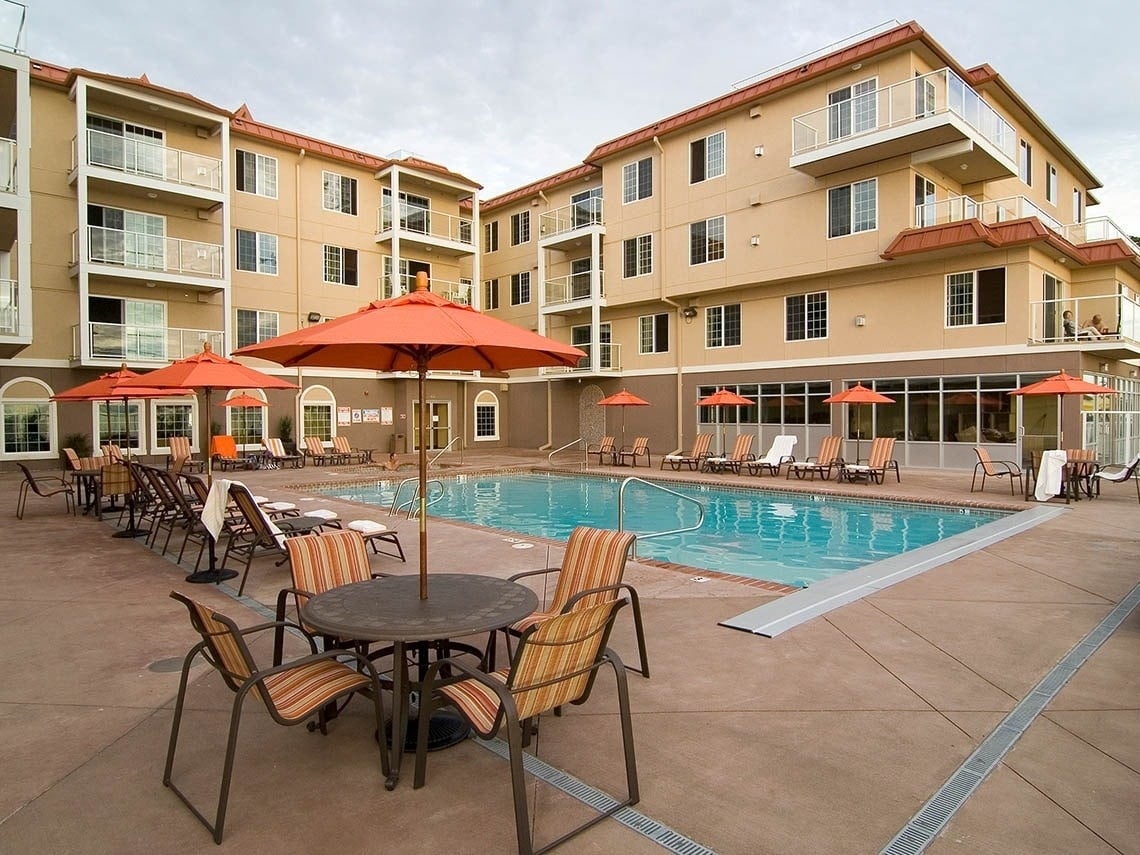 Travel Raintree Corpo: Hotel outdoor pool with lounge chairs and orange umbrellas.