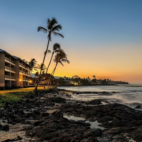 Beachfront hotel resort in Hawaii at sunset, with palm trees and ocean views.