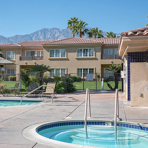 Relax at Travel Raintree Corpo with its inviting pool and spa, framed by palm trees and mountains.