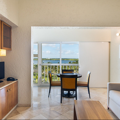 Travel Raintree Corpo room: dining table, balcony view, sofa, and TV.