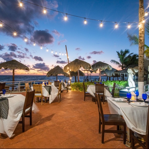 Travel Raintree Corpo: Beachfront dining under string lights at sunset.