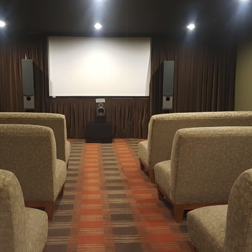 Travel Raintree Corpo private cinema room with plush seating and large screen.
