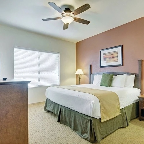 Travel Raintree Corpo: Cozy hotel room with king bed, TV, and ceiling fan.