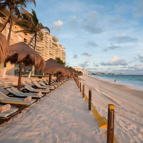 Travel Raintree Corpo: Beachfront resort with palapa umbrellas, lounge chairs, and ocean views.