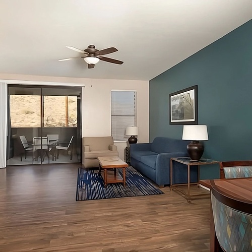 Travel Raintree Corpo living room with blue sofa and patio view.