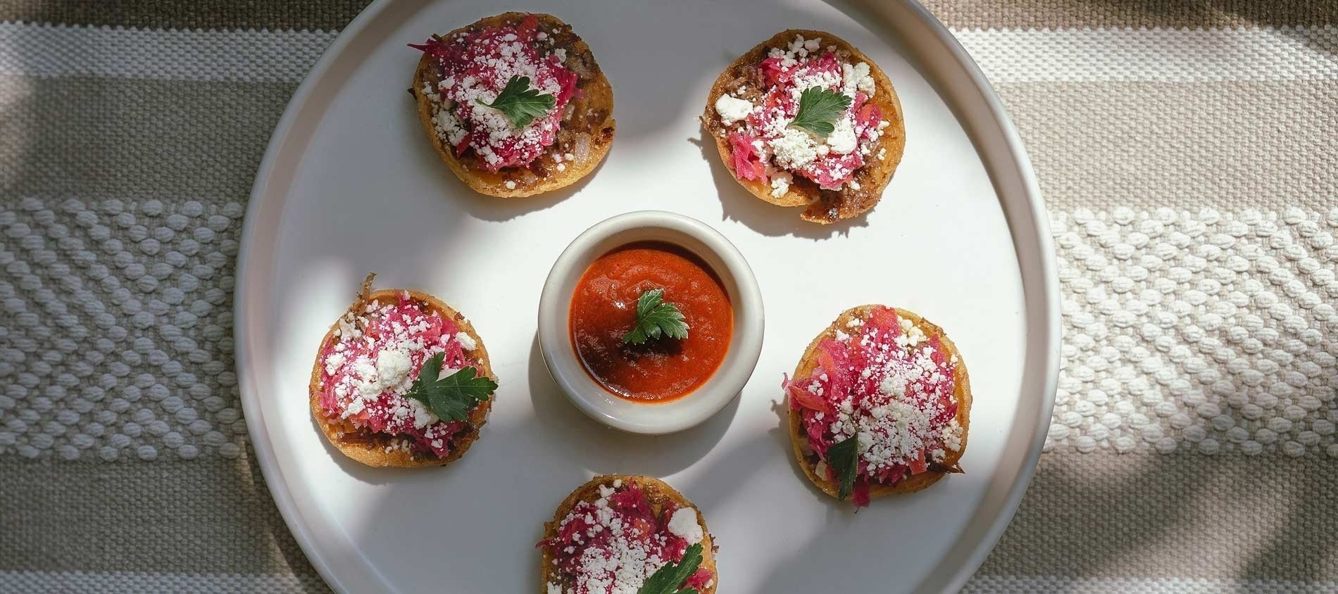 un plato blanco con tostadas y un tazón de salsa