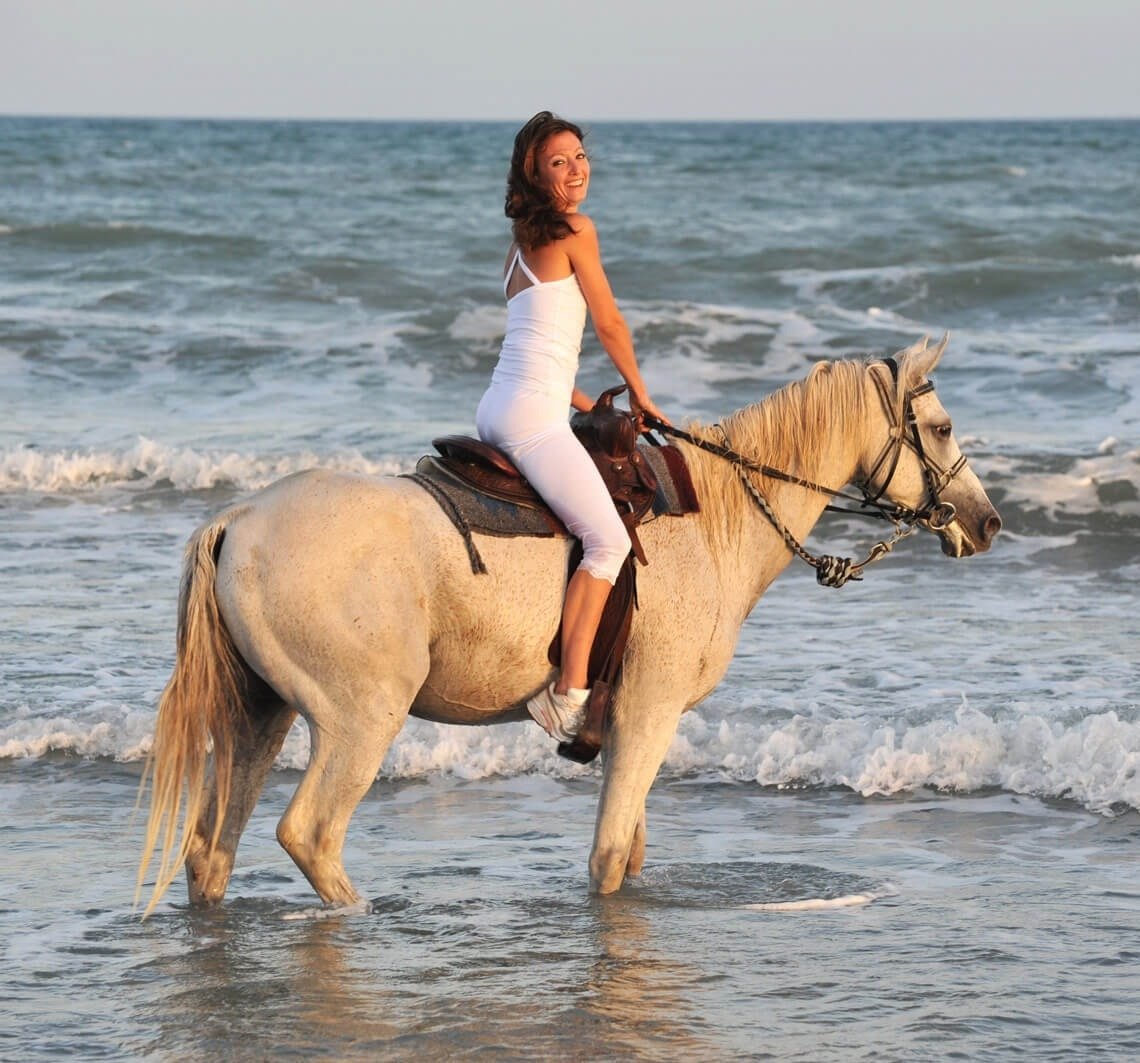 a woman is riding a brown horse with a pink saddle