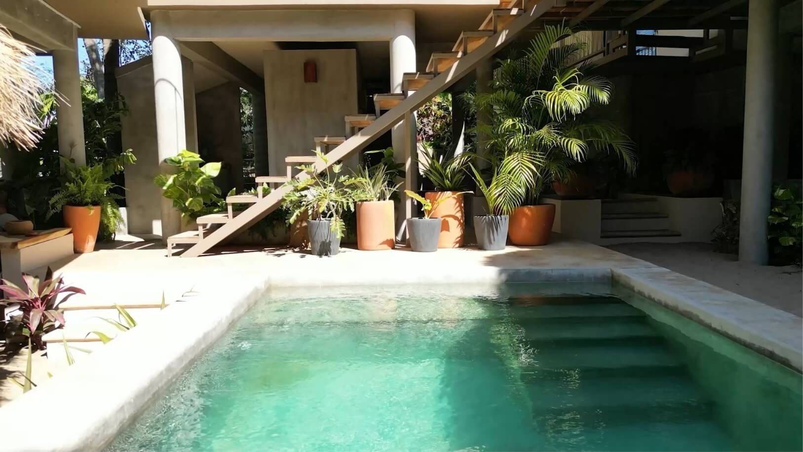 a swimming pool surrounded by potted plants and stairs