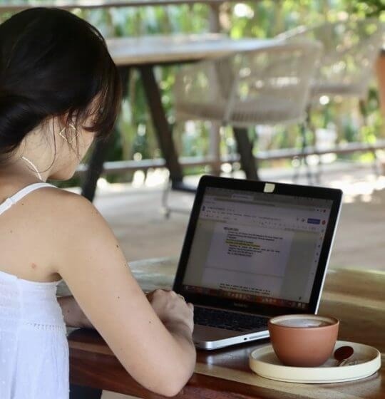 una mujer está sentada en una mesa con una computadora portátil y una taza de café .