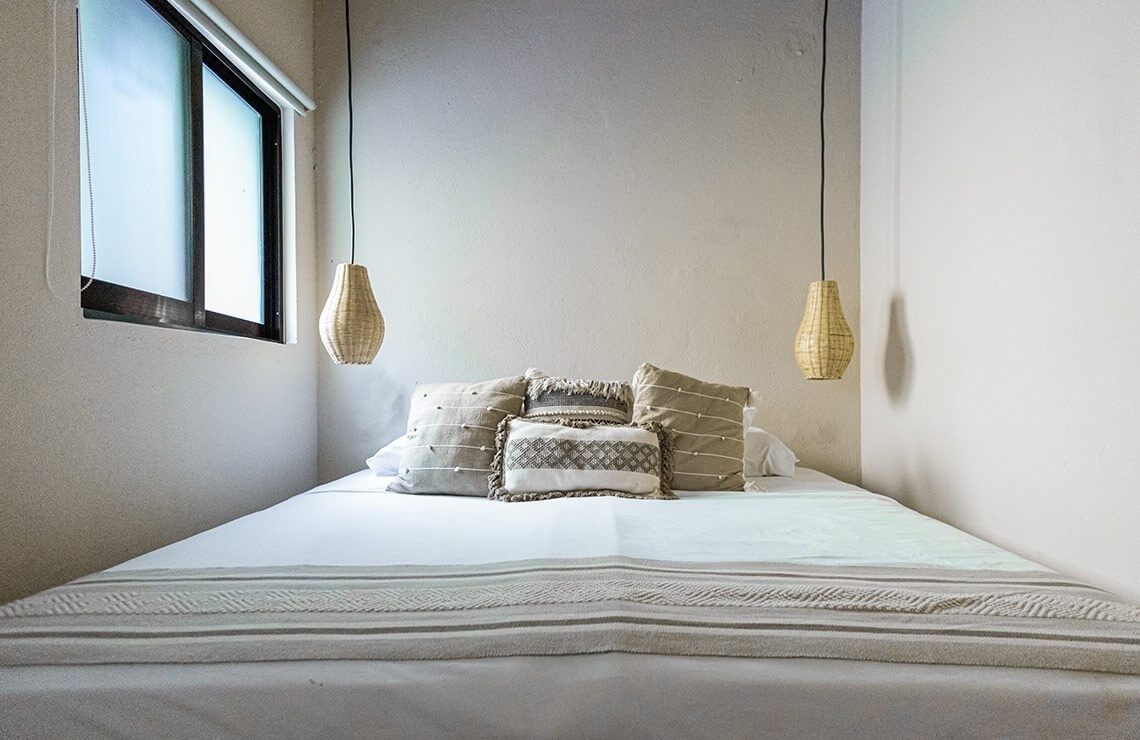 a bed with a white blanket and pillows hanging from the ceiling