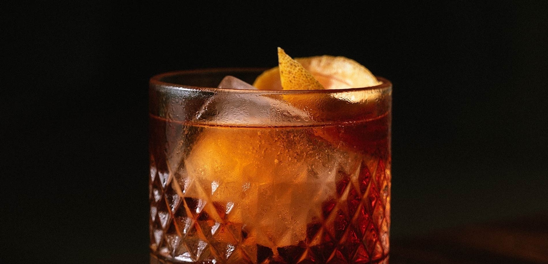 a close up of a glass with ice and a slice of orange