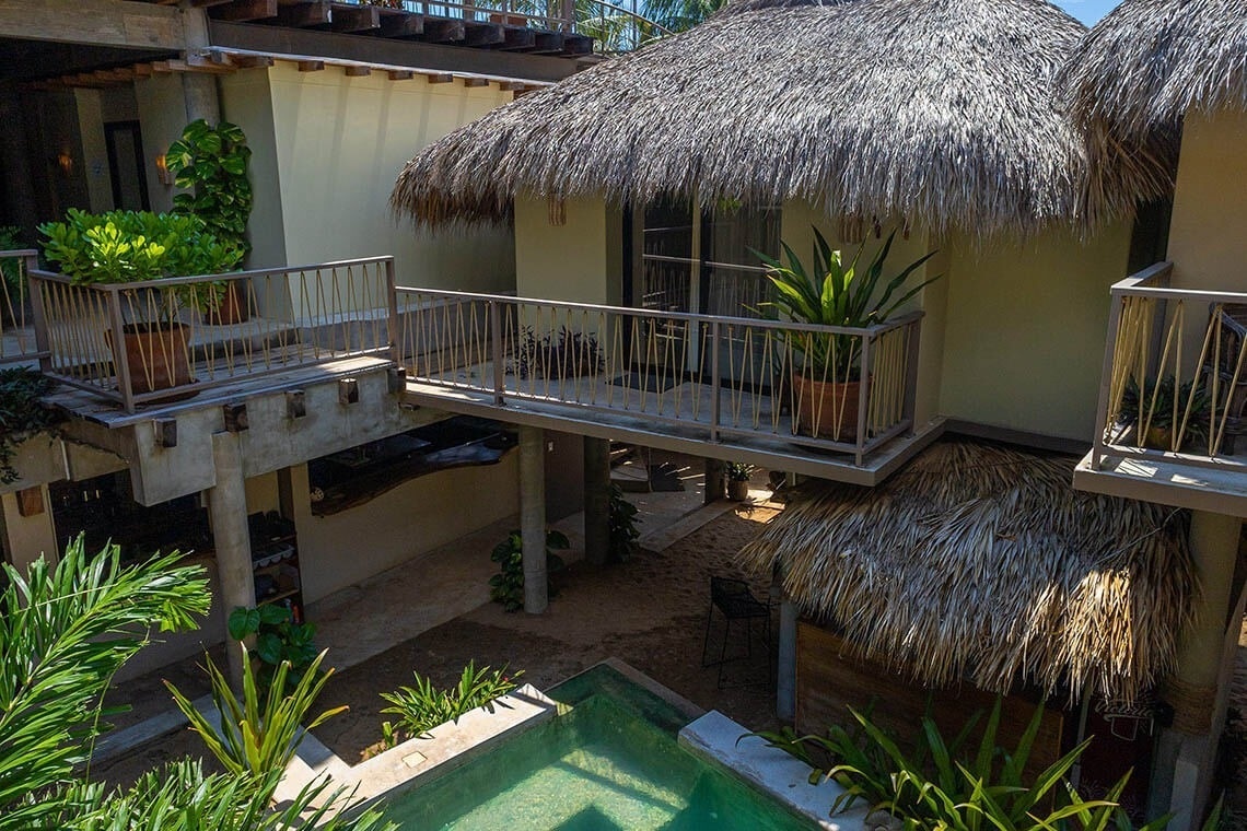 a balcony overlooking a pool with a thatched roof