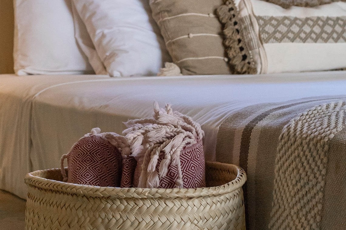 a basket filled with blankets sits next to a bed