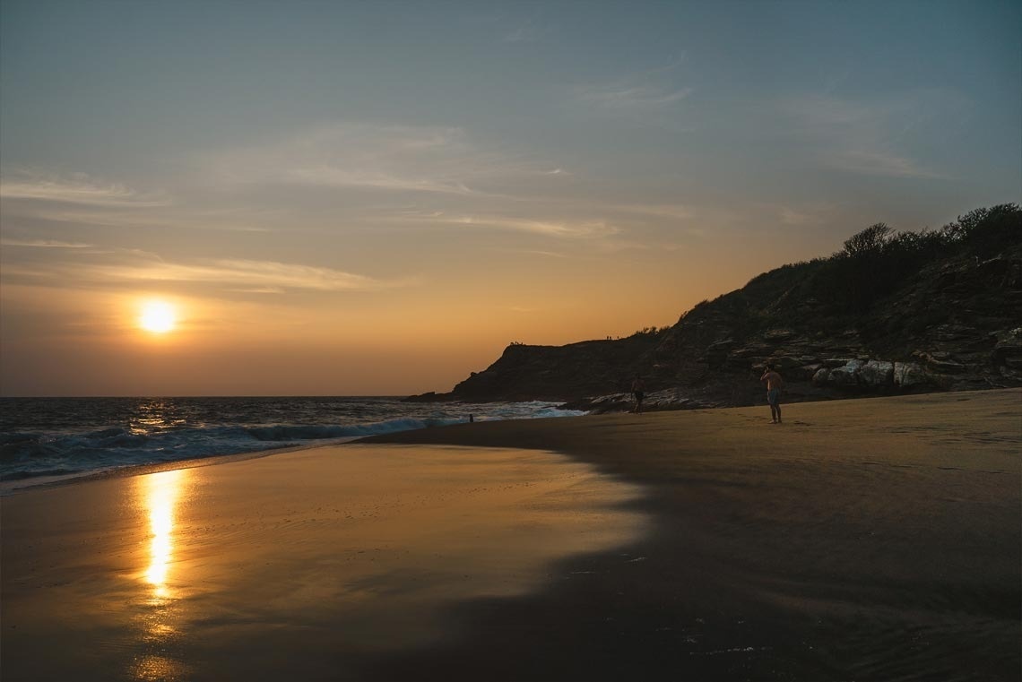 un hombre camina por la playa al atardecer