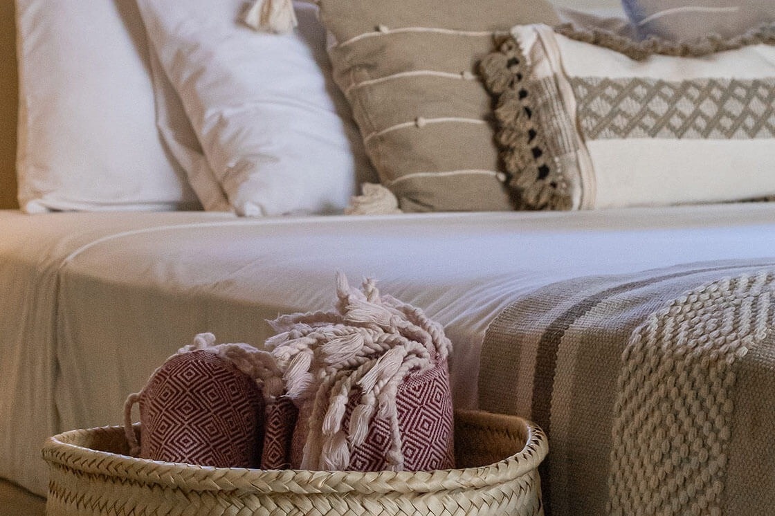 a basket of slippers sits on a bed next to a blanket