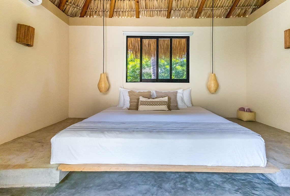 a bed in a room with a thatched roof