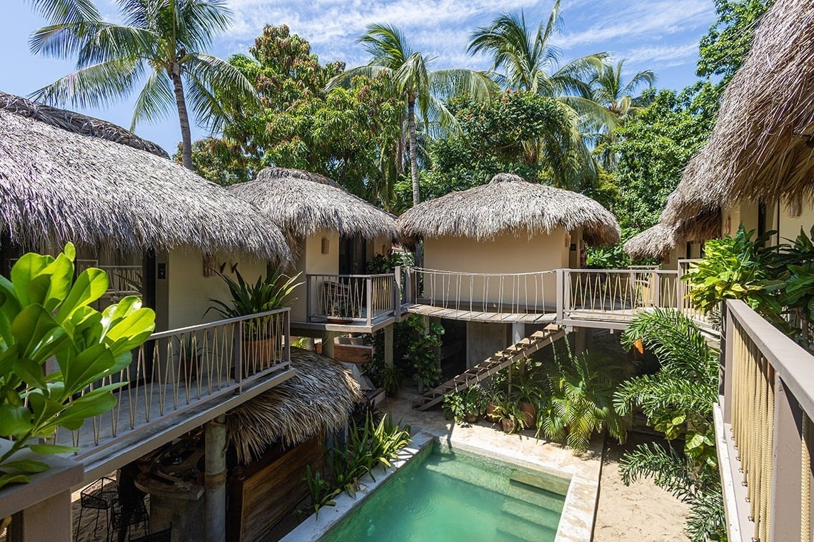 a swimming pool is surrounded by thatched roofed buildings