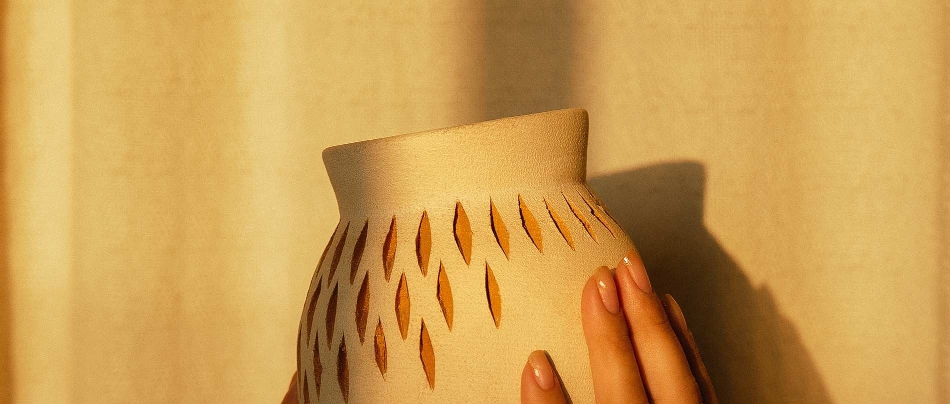 a woman holds a vase with a pattern on it