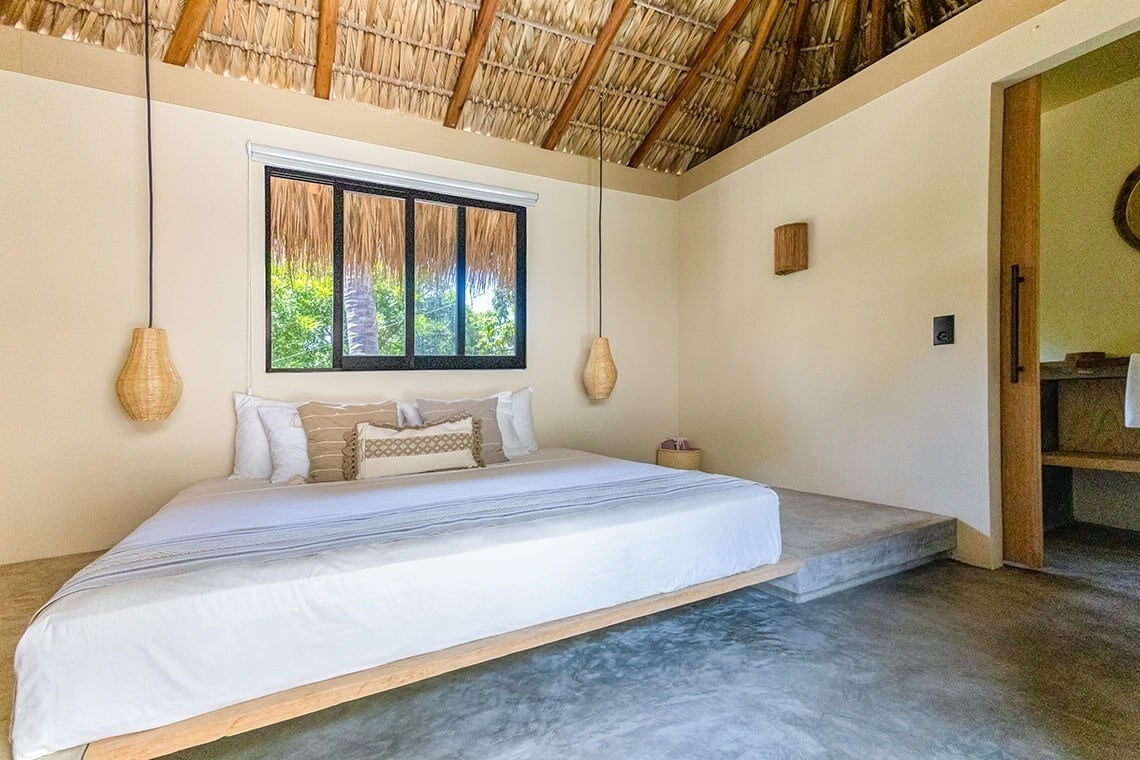 a bed in a room with a thatched roof