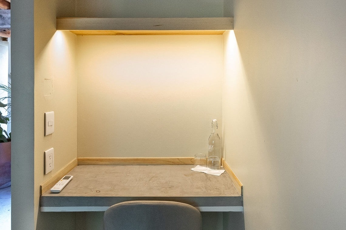 a small desk with a bottle of water and two glasses on it