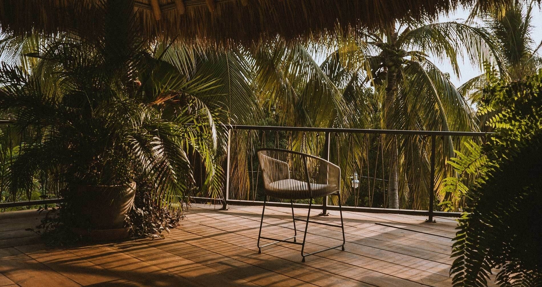 a chair on a balcony with palm trees in the background