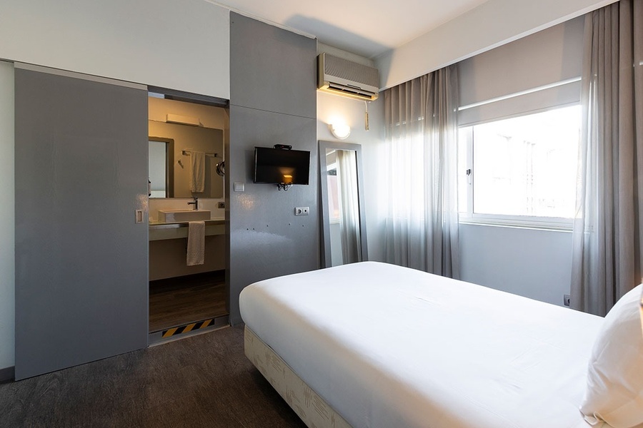 um quarto de hotel com cama e televisão