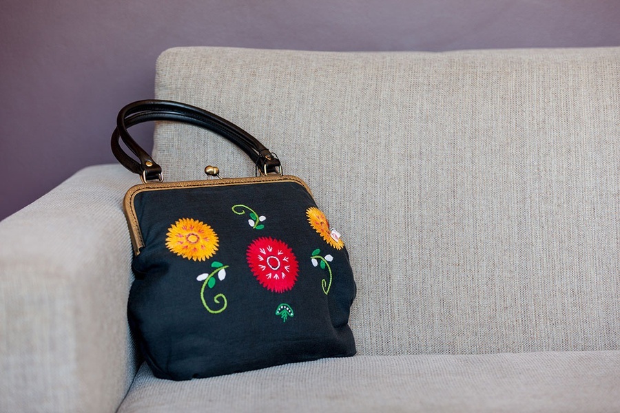 uma bolsa preta com flores bordadas está sobre um sofá