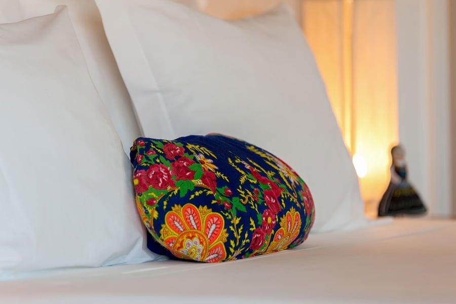 um travesseiro colorido está sobre uma cama branca