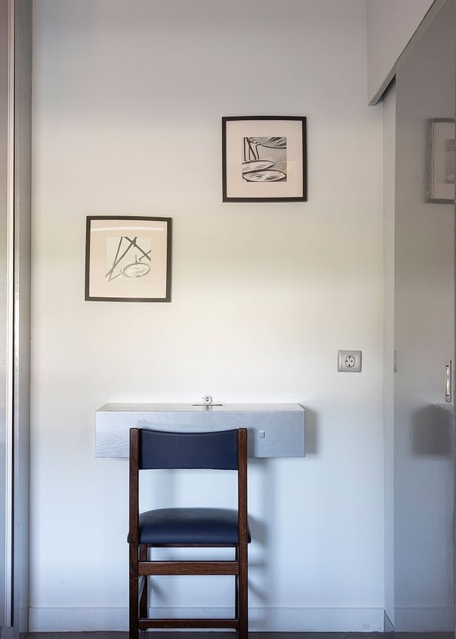 uma cadeira ao lado de uma mesa com dois quadros pendurados na parede