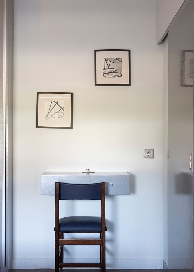 a chair sits in front of a desk with two framed pictures on the wall above it