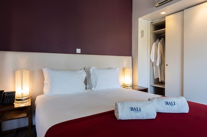 a hotel room with a bed and two towels that say ' rali hotel ' on them