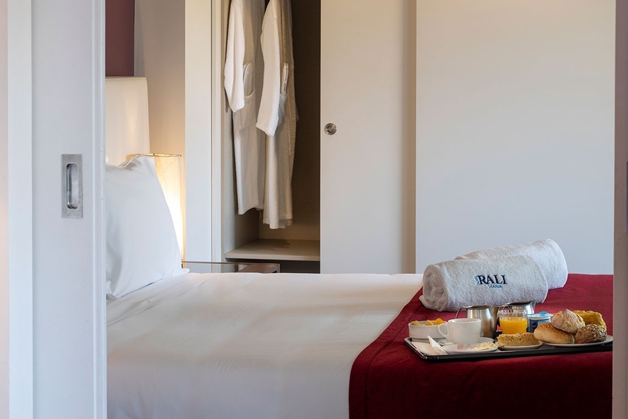 a bed with a tray of food and a towel that says ' rali ' on it