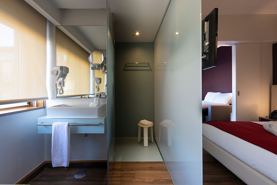 um banheiro com uma pia e um espelho ao lado de uma cama
