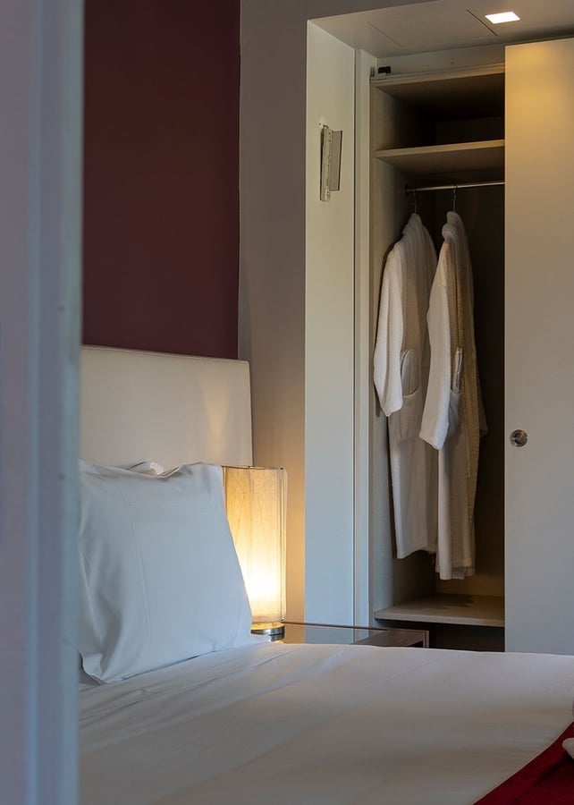 une chambre avec un lit et un placard avec des vêtements suspendus