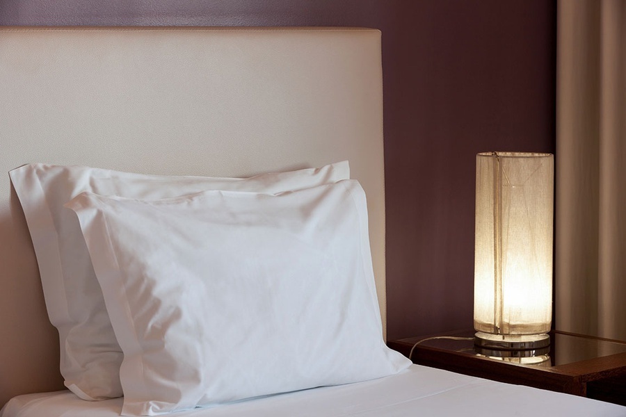 uma cama com travesseiros brancos e uma lâmpada ao lado