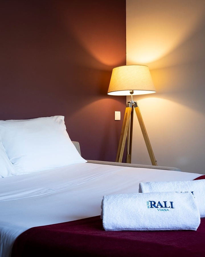 una habitación con una cama y una lámpara y una toalla que dice rali
