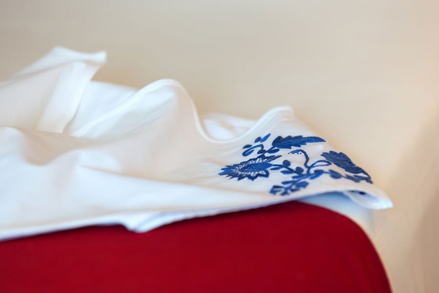 uma camisa branca com bordado azul está sobre uma mesa vermelha